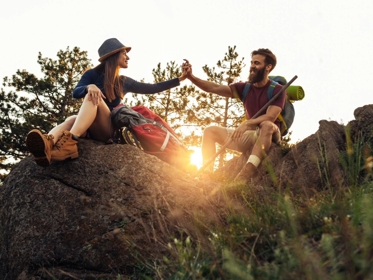 Wanderpaar sitzt vor Sonnenuntergang auf Felsgipfel