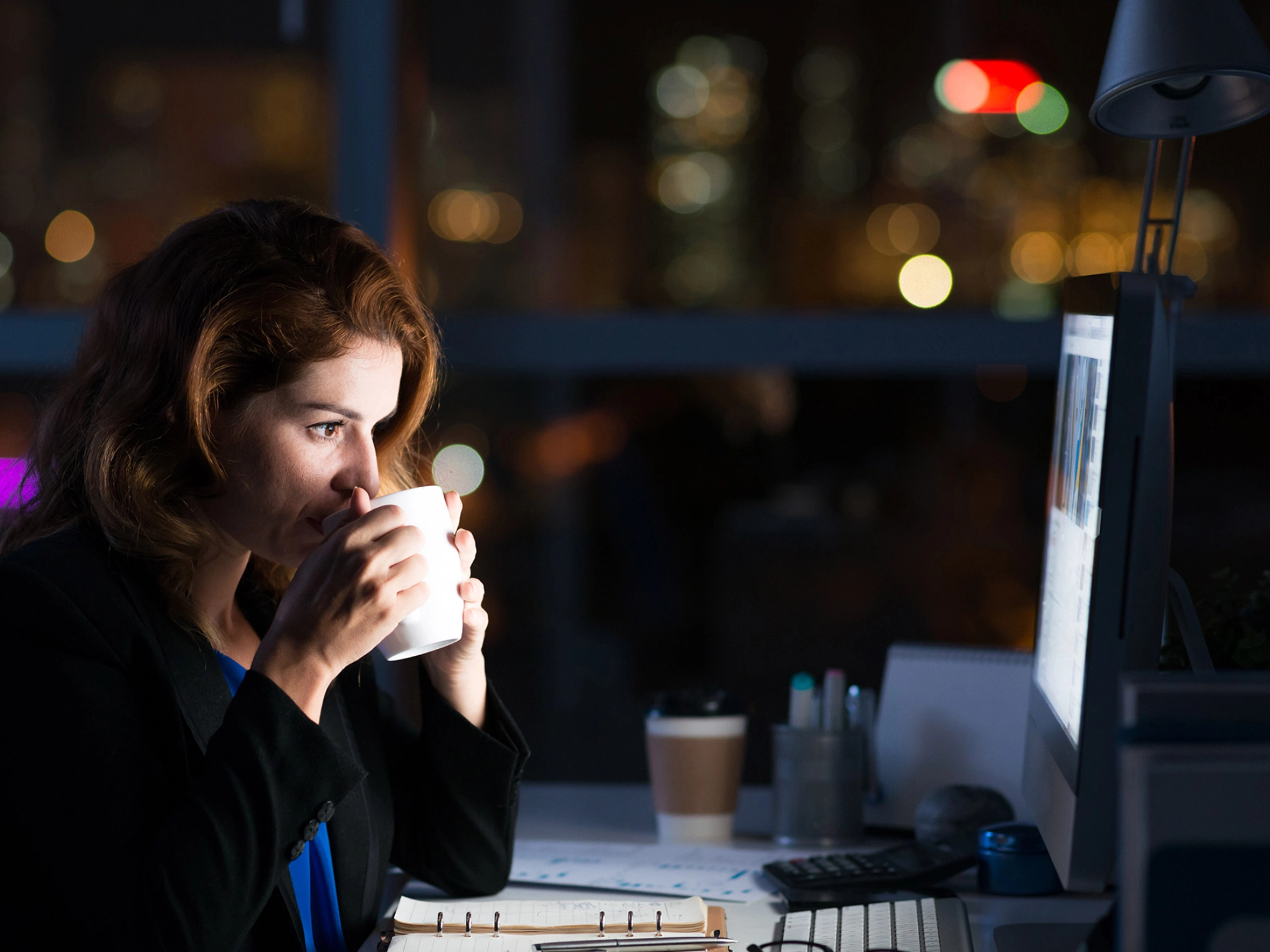 Eine Frau im Büro arbeitet Nachts am Computer
