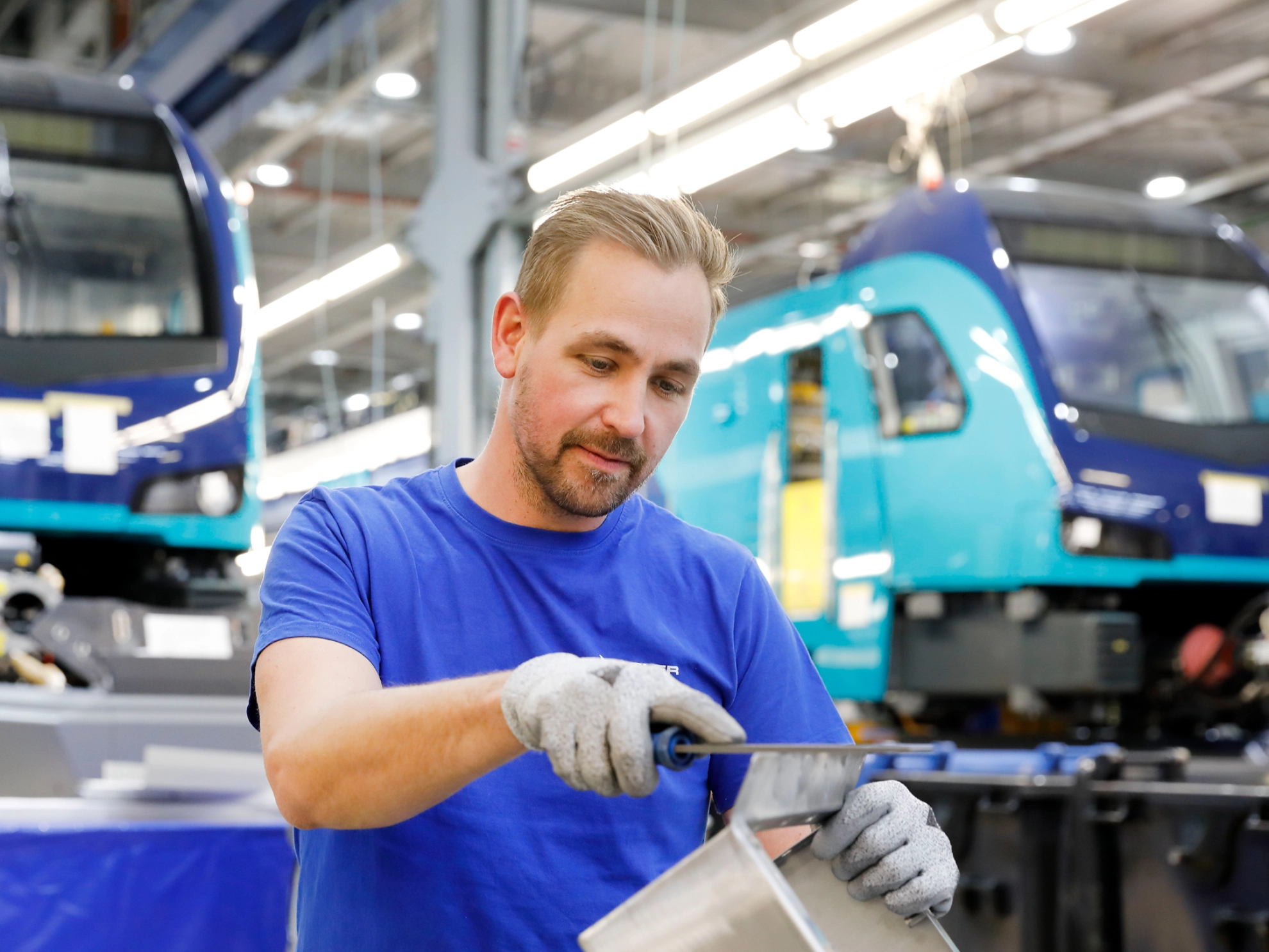 Ein Mitarbeiter feilt ein Metallteil beim Hersteller von Schienenfahrzeugen Stadler in Berlin